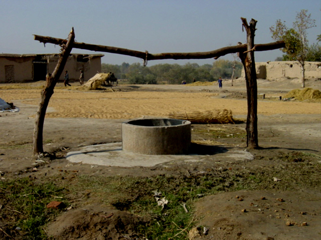 A Well with Wheat Drying Behind It